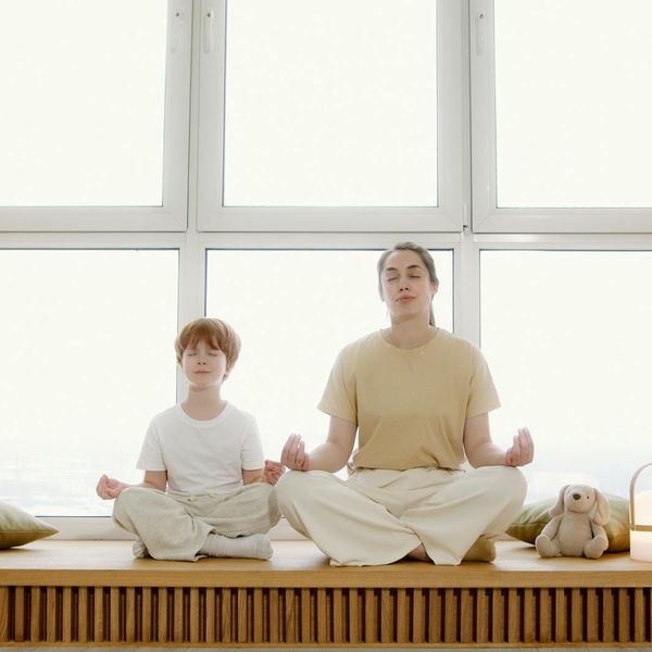A child sitting peacefully in a yoga pose with closed eyes.