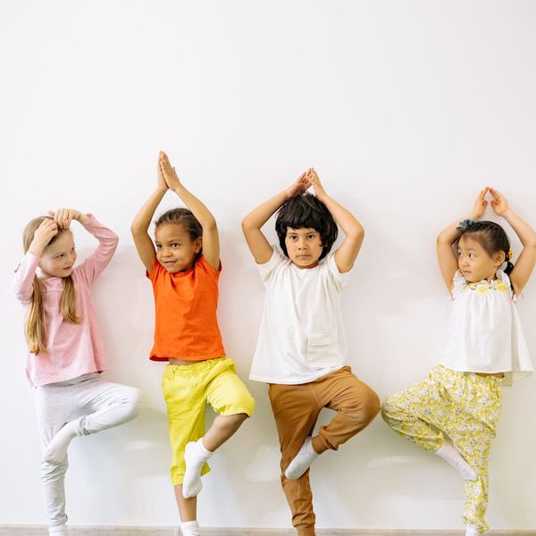Group of diverse children laughing and stretching on yoga mats.