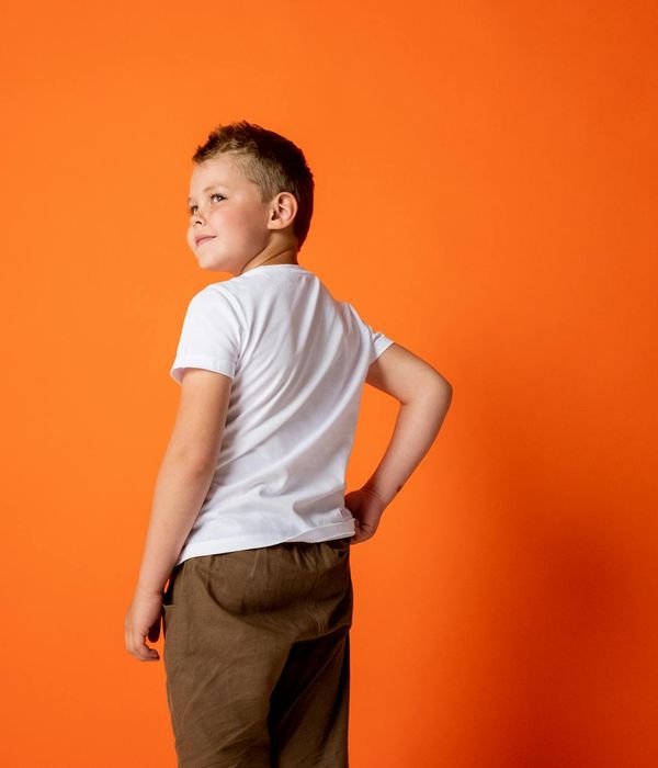Smiling child doing a tree yoga pose in a bright studio.